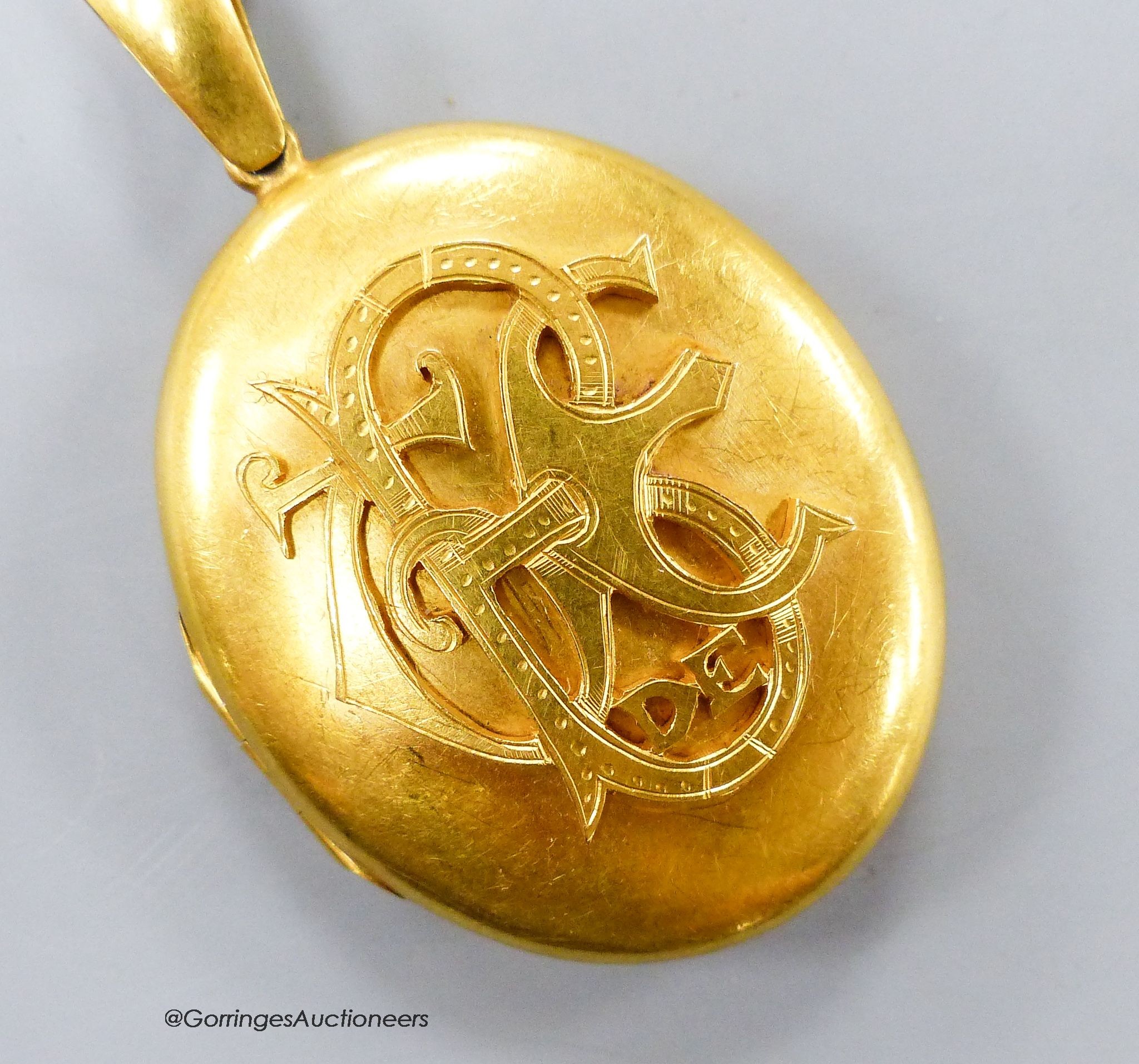 A Victorian yellow metal oval pendant locket with applied monogram, overall 63mm, gross weight 31.9 grams.